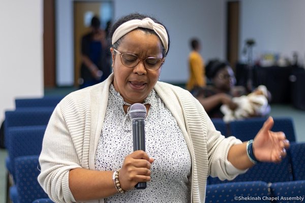 A church mother leads the congregation in prayer.