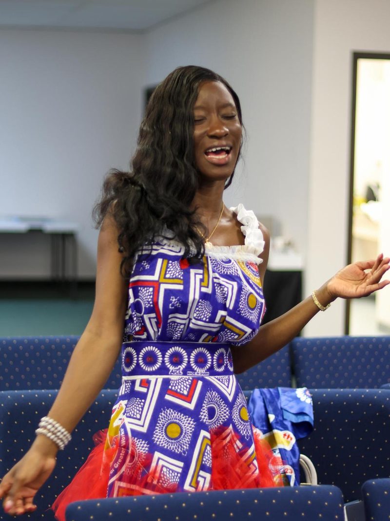 A young woman singing with her arm outstretched during praise.