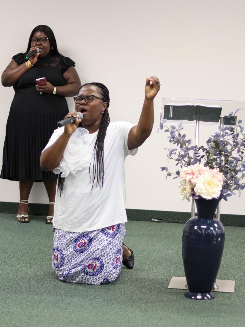 A woman kneeling in prayer at the front of the sanctuary.