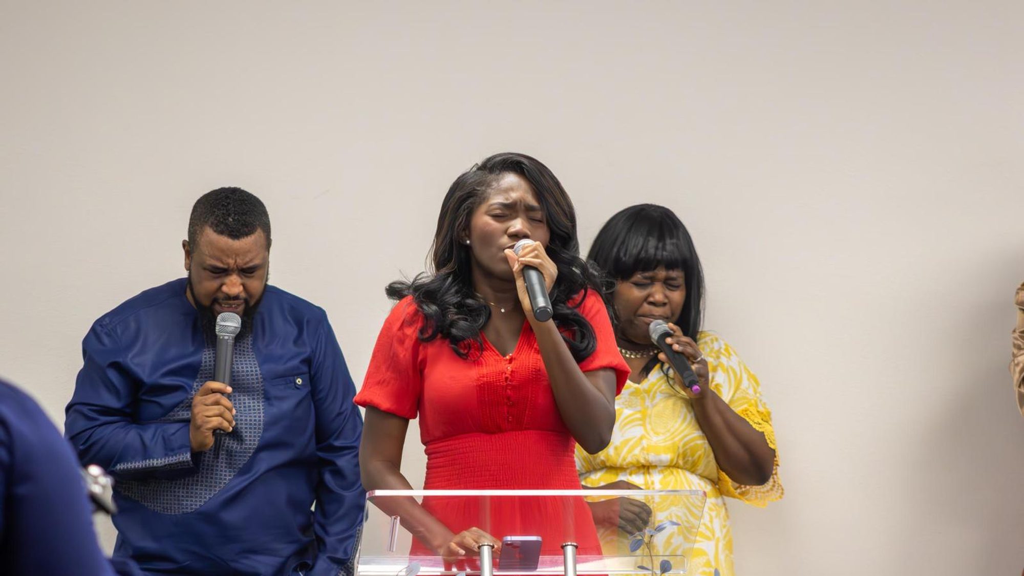 Three worship leaders singing together at the front of the sanctuary.